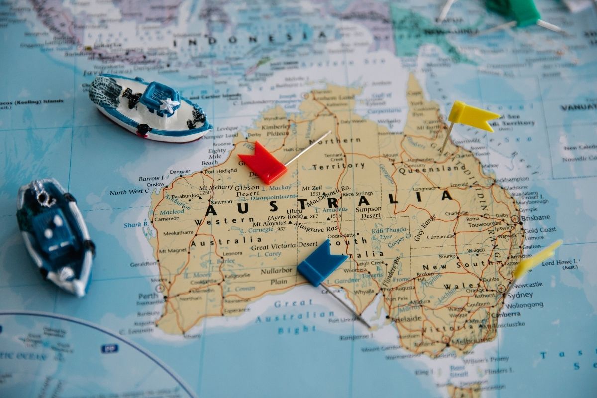Map of Australia with toy boats and flags on a world map background
