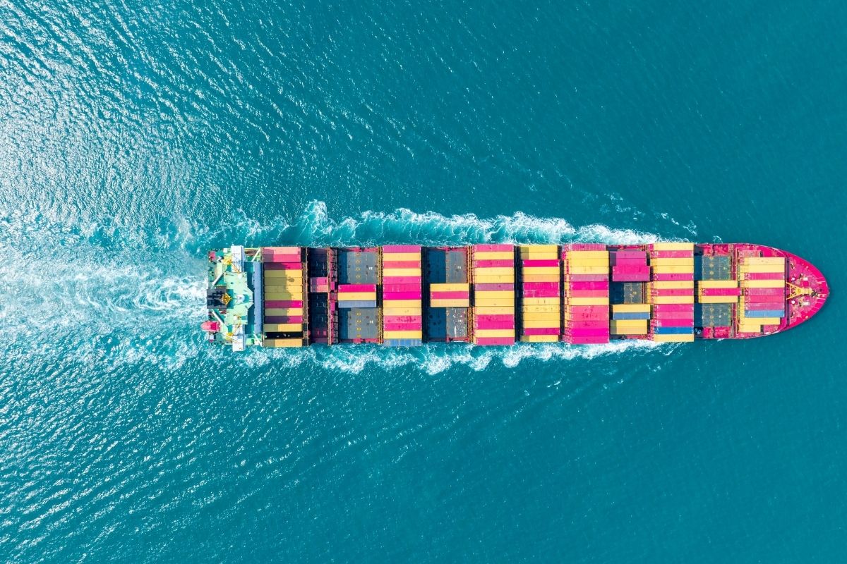 A container ship with colorful cargo containers sailing on a blue ocean.